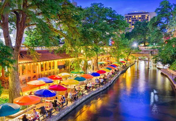 A riverside dining area with outdoor seating and umbrellas.