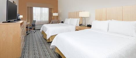 A hotel room with two beds, a desk with a television, a chair, and a desk lamp.