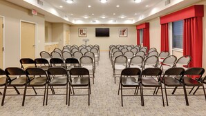 A conference room with rows of chairs, a flat-screen TV, and a carpeted floor. - Holiday Inn Express & Suites San Antonio - Brooks City Base by IHG (San Antonio)