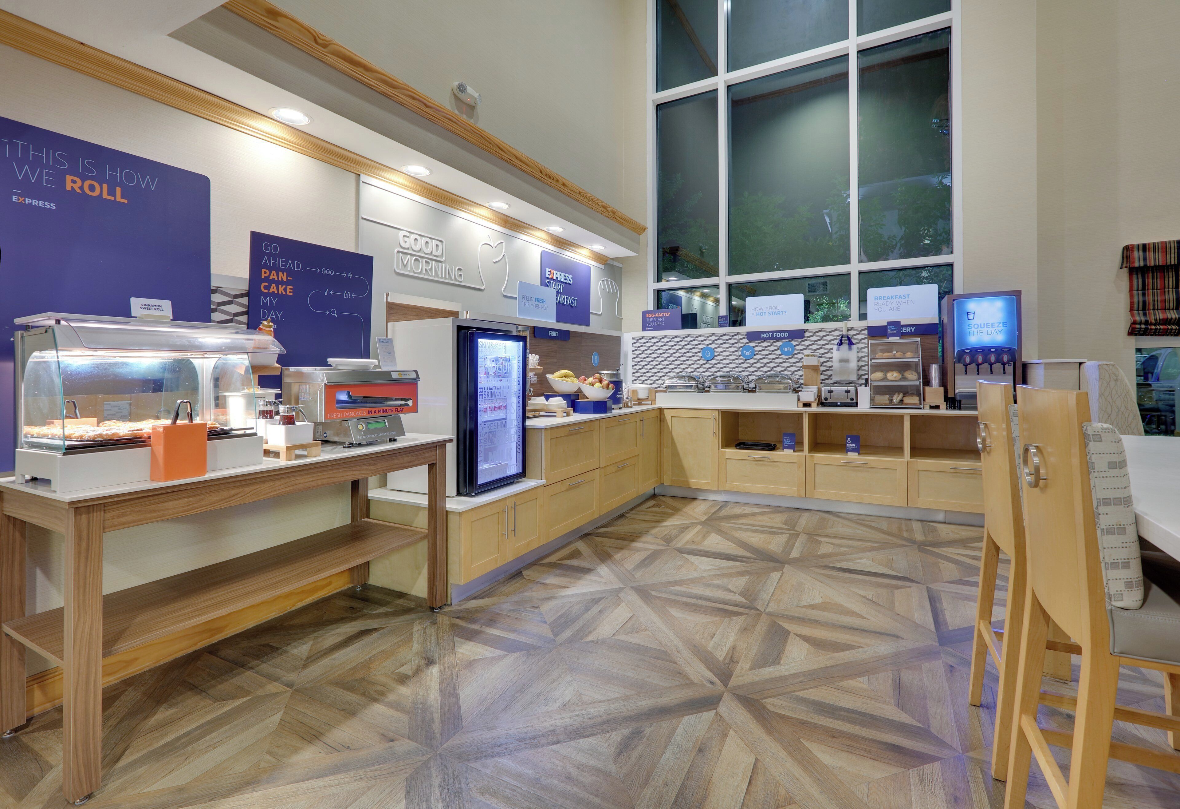 A breakfast area with a counter, display cases, and a digital menu board.