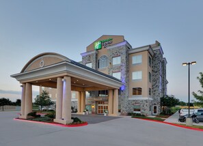 A Holiday Inn Express hotel with a covered entrance, stone facade, and a clear sky. - Holiday Inn Express & Suites San Antonio - Brooks City Base by IHG (San Antonio)