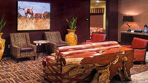 A room with a large bed, two chairs, a small table, and two large vases.