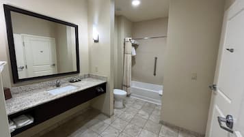 Un baño con lavamanos, espejo, inodoro y zona de ducha.