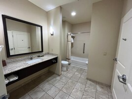 Un baño con lavamanos, espejo, inodoro y zona de ducha.