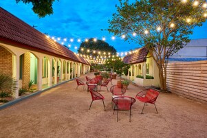 A courtyard with outdoor seating, string lights, and a tree.