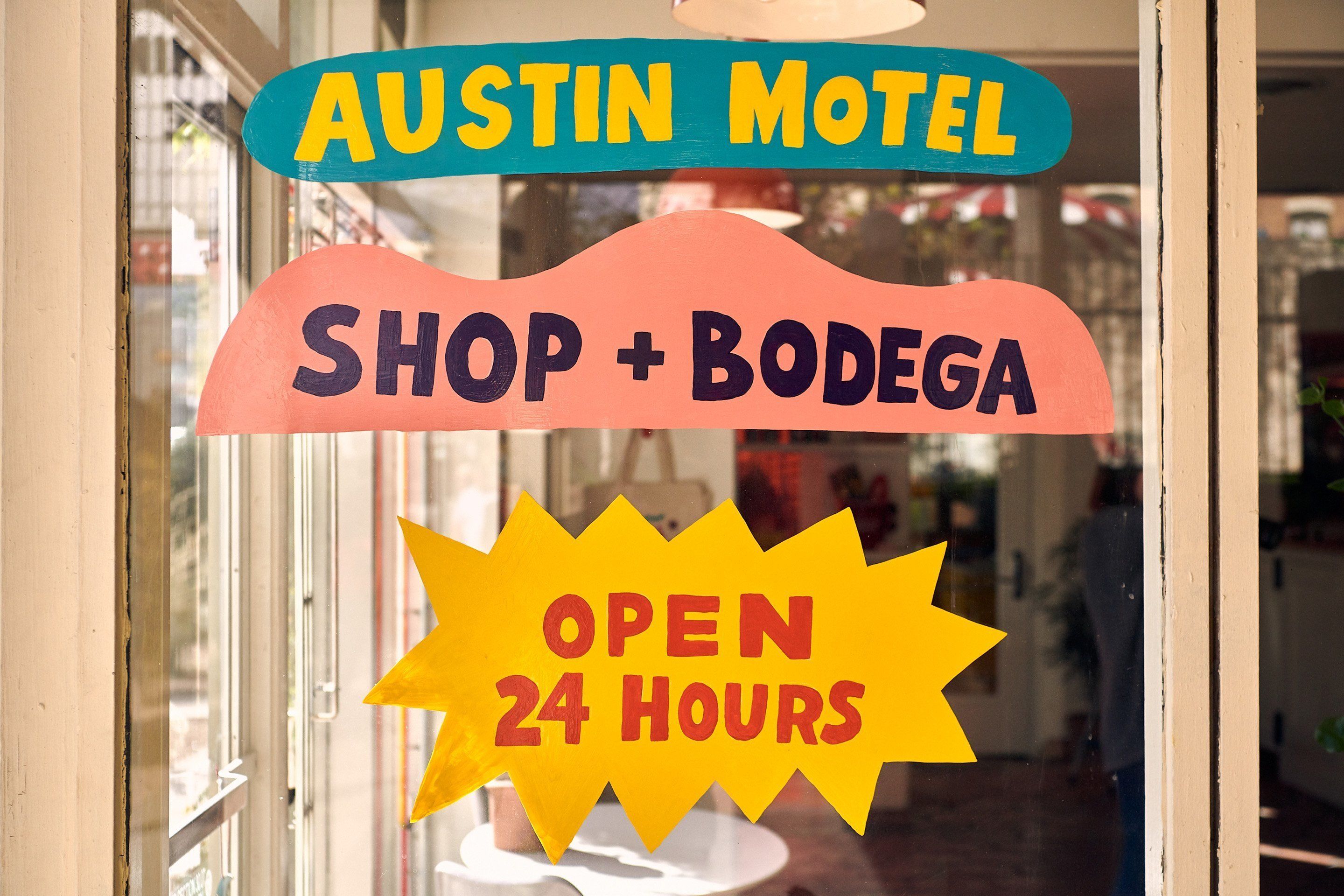 Señal del Austin Motel, con Shop + Bodega y aviso de atención 24 horas.