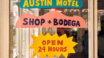 Señal del Austin Motel, con Shop + Bodega y aviso de atención 24 horas.
