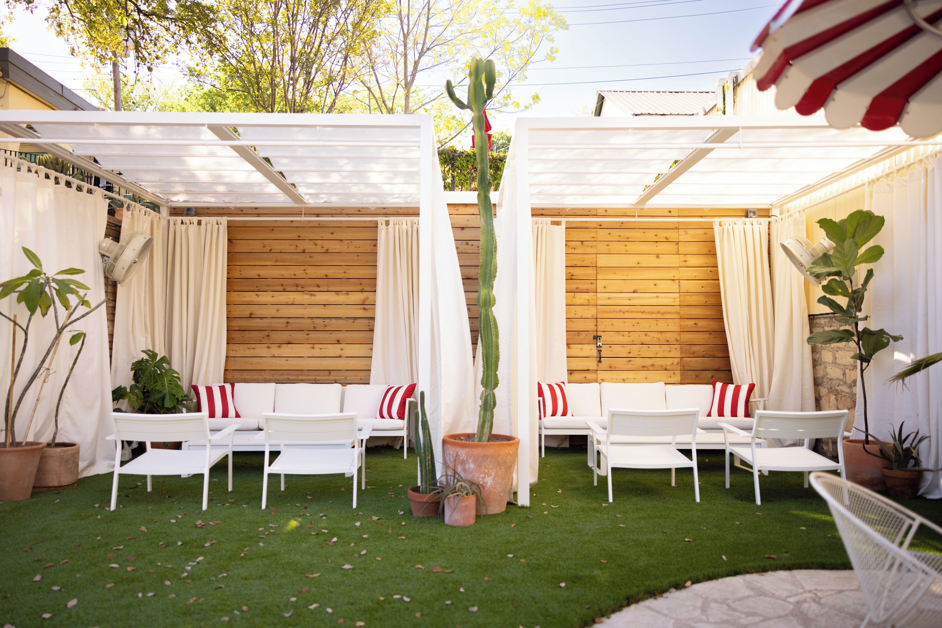 Un patio con mobiliario blanco y un cactus como pieza central.