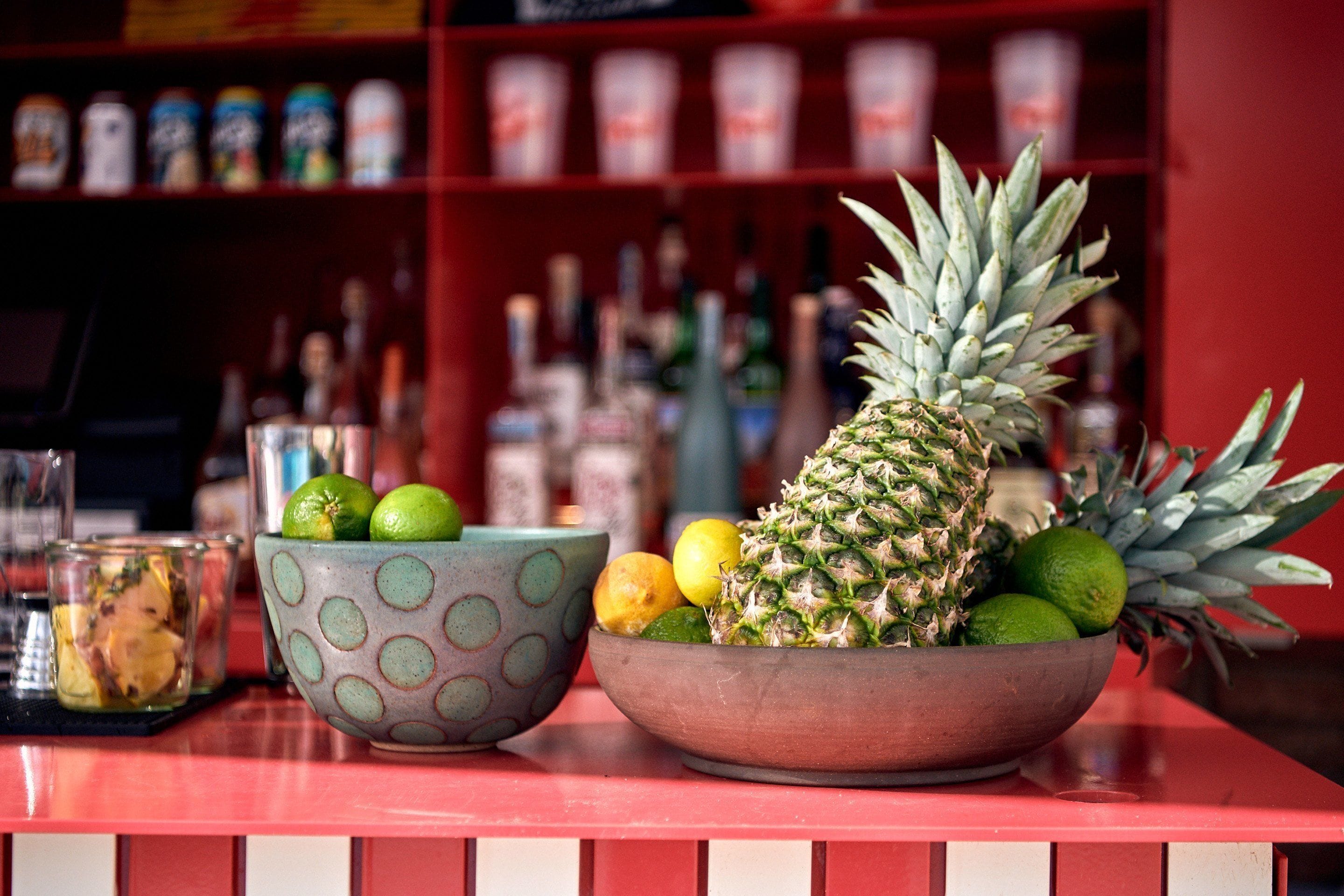 Balcão de bar com uma tigela de frutas e um copo de bebida.