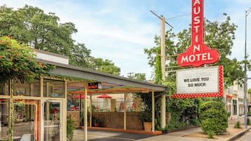 A motel with a large neon sign reading "AUSTIN MOTEL" and a smaller sign below stating "WE LOVE YOU SO MUCH".