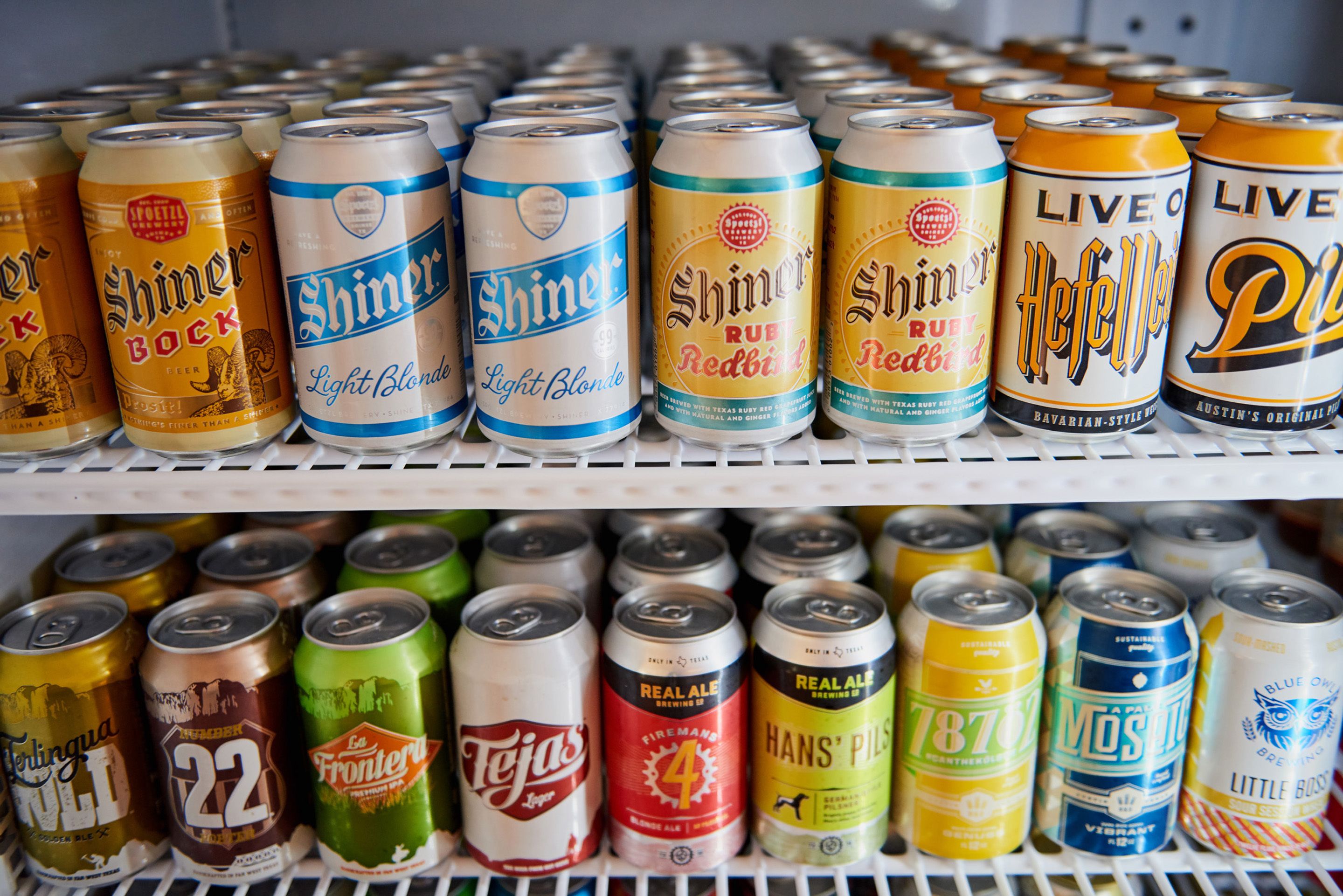 Mostrador refrigerado con diversas latas de cerveza.