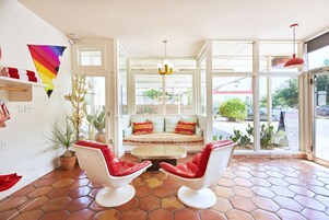 A bright room with a white sofa, two red chairs, a coffee table, and a large window.