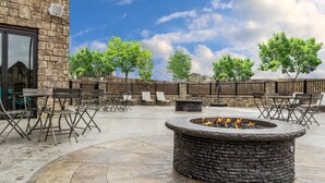 Une terrasse extérieure avec un sol en pierre, un foyer et des sièges d’extérieur.