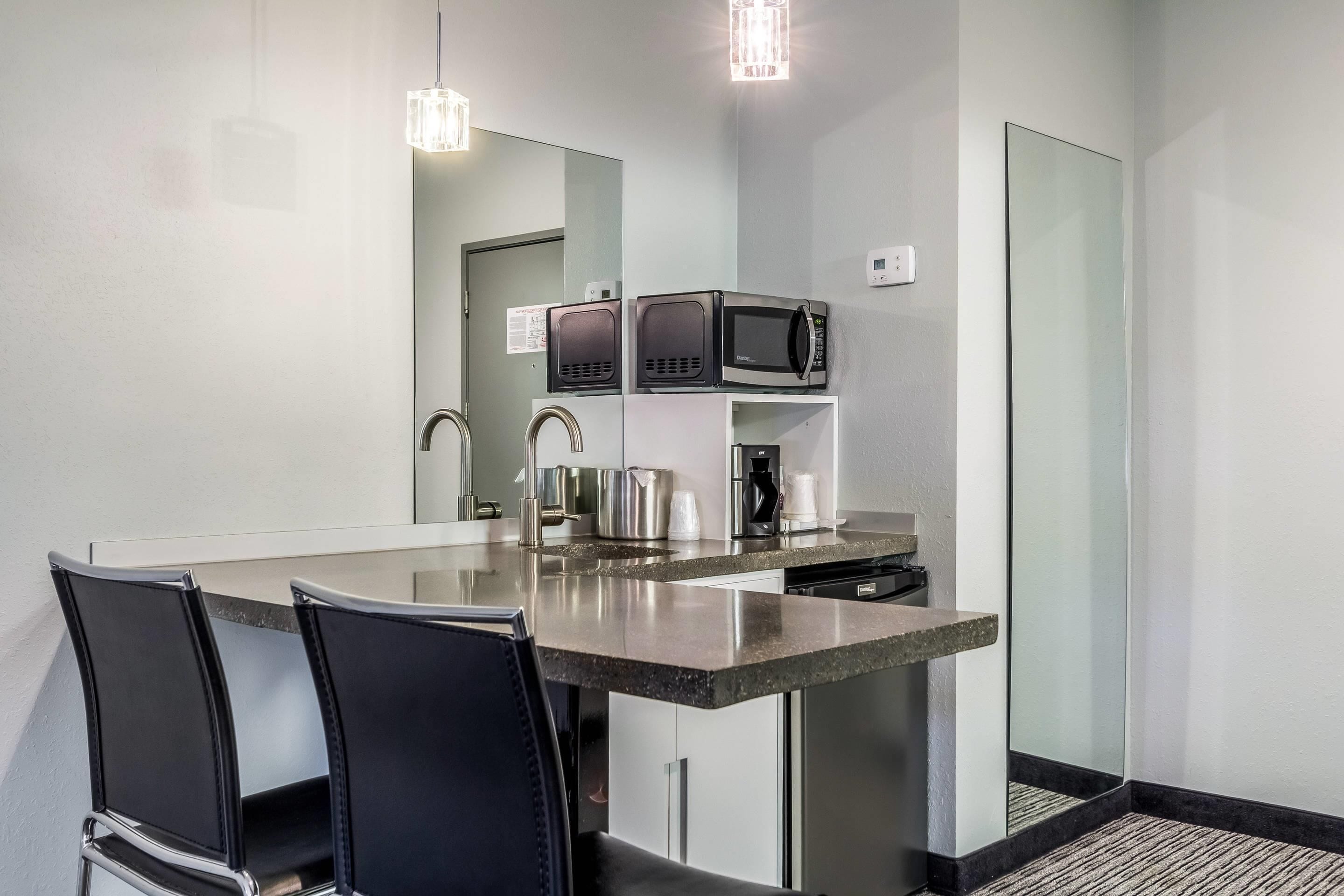 A modern kitchen with a central island, stainless steel appliances, and black chairs.