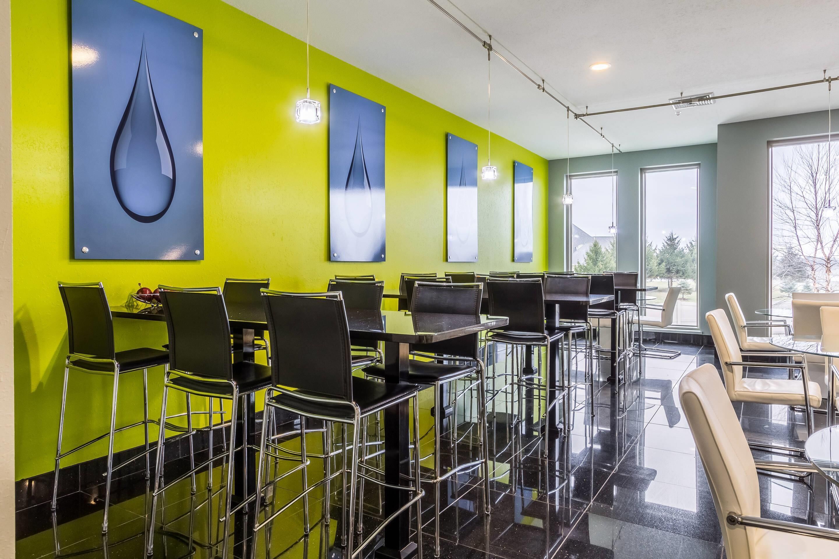 A modern restaurant with high tables and chairs, bright green walls, and large windows.