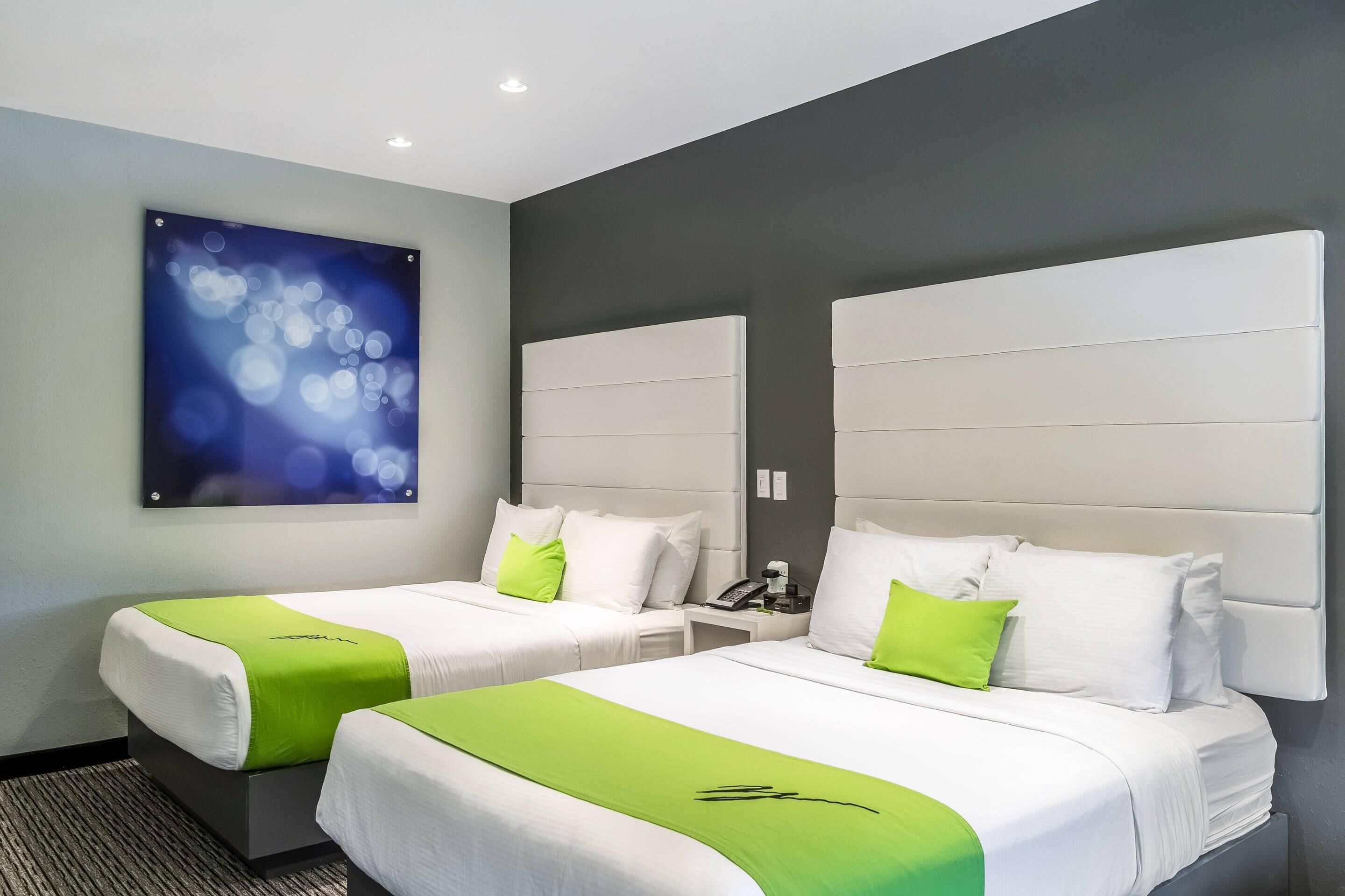 A hotel room with two beds, a large abstract painting, and a modern design.