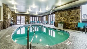 Une piscine intérieure avec des murs en pierre, une eau cristalline et de nombreuses fenêtres.