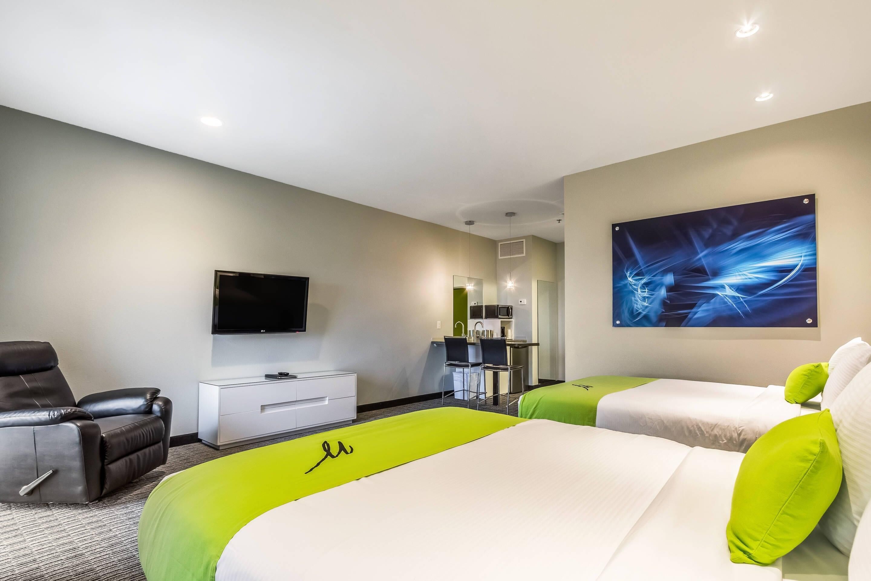 A hotel room with a bed, a TV, a desk, and a chair.