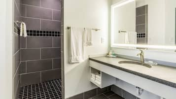 Un bany modern amb dutxa, un lavabo amb mirall i un escurapous.