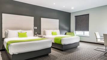A modern hotel room with two beds, a large window, and a seating area.