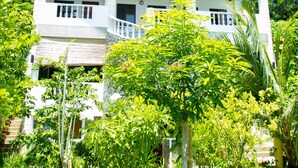 Un hotel de varios pisos con balcones, rodeado de abundante vegetación.