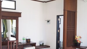 A compact hotel room with a wooden desk, a small refrigerator, a mirror, and a wooden partition. - Needa Rock Resort (Khanom)