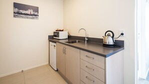 A compact kitchen with a sink, a kettle, a toaster, and a refrigerator. - 123 Motel (Christchurch)