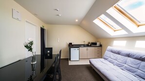 A compact room with a kitchenette, a dining area, and a sofa. - 123 Motel (Christchurch)