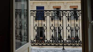 A window with a view of a building with balconies and a dome structure.