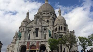 Un grand bâtiment historique, doté de plusieurs dômes et statues, entouré d’une foule de personnes.
