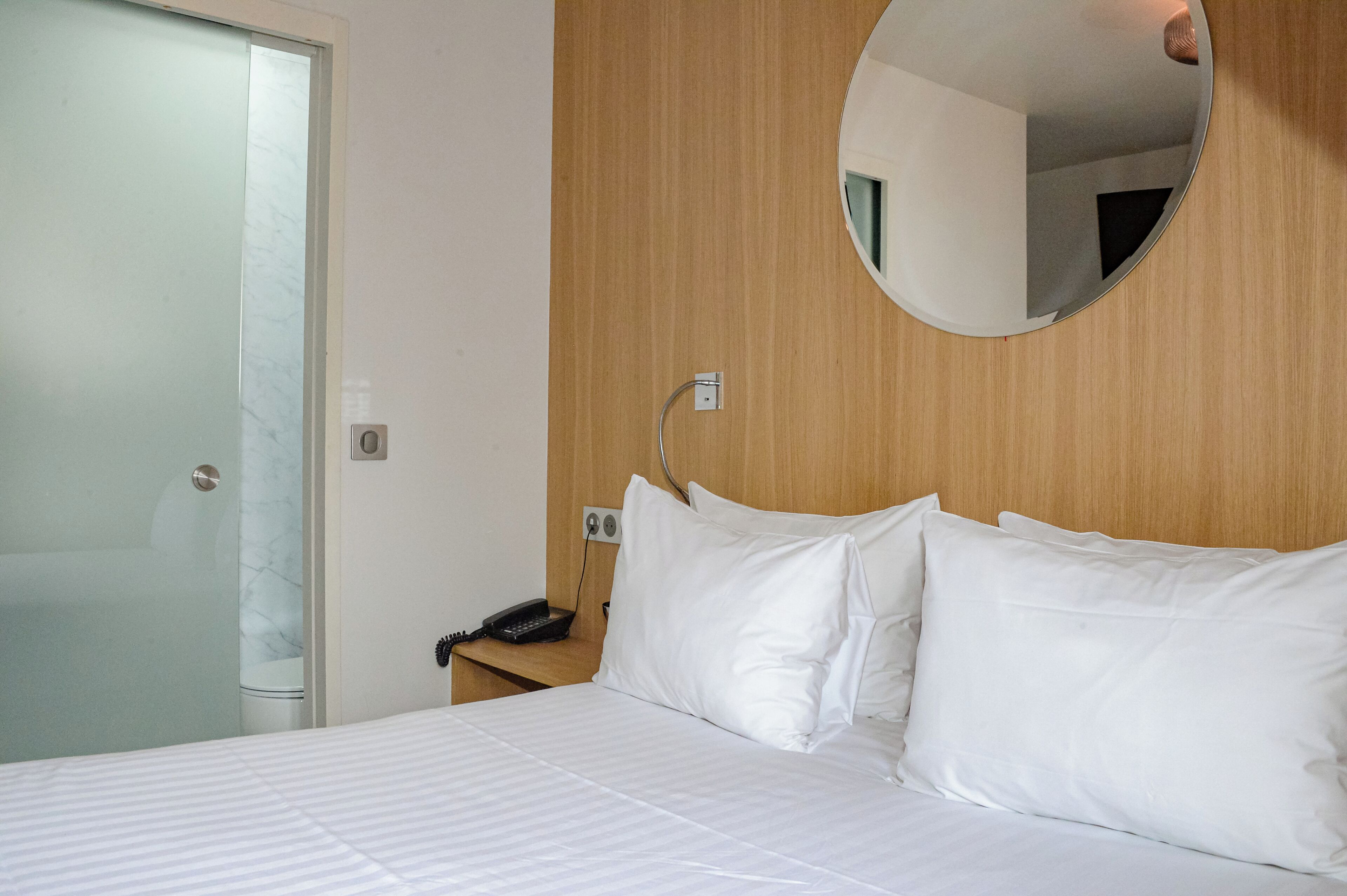 Ein Hotelzimmer mit einem Bett, einem Nachttischtelefon und einem Spiegel an der Wand.