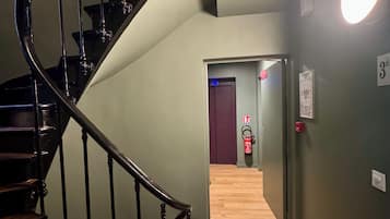 A spiral staircase with wooden steps and black railings leading to a landing.