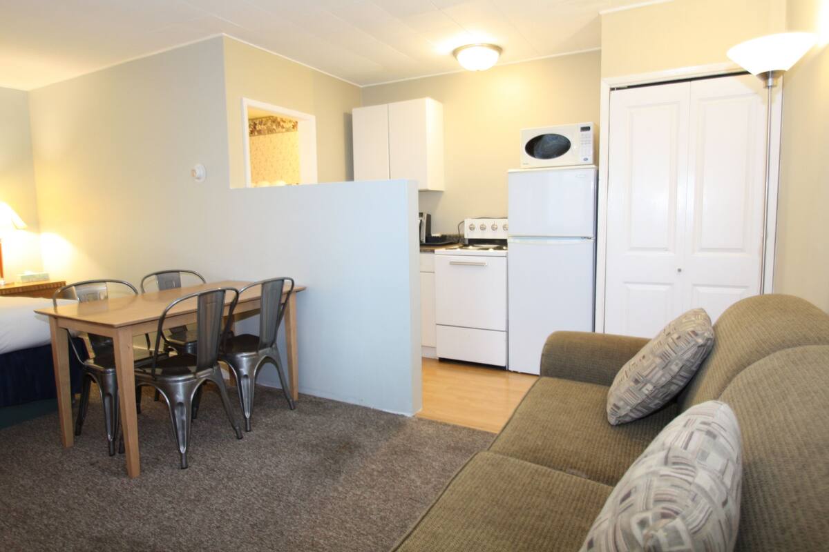 A compact living space with a dining area, kitchenette, and a sofa.