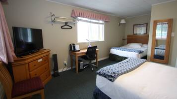 A hotel room with a bed, a desk with a chair, a television, a window with a curtain, and a mirror.