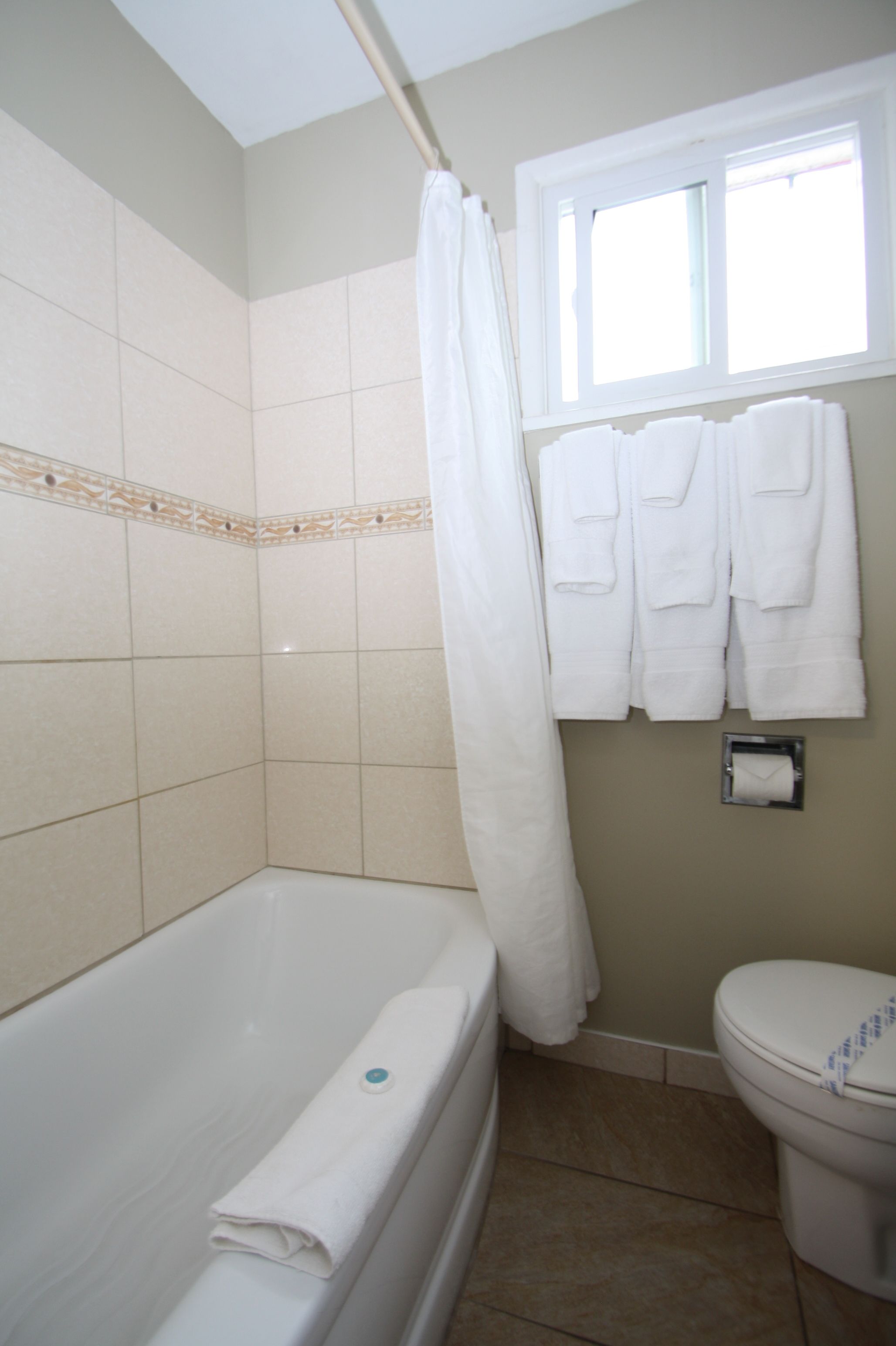 Un baño con bañera, inodoro y ventana.