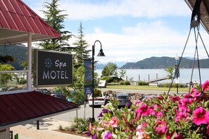 A motel sign with a view of mountains and a lake.