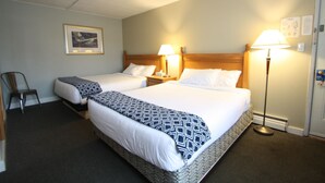 A hotel room with two beds, a framed picture on the wall, and a desk lamp. - Harrison Spa Motel (Harrison Hot Springs)