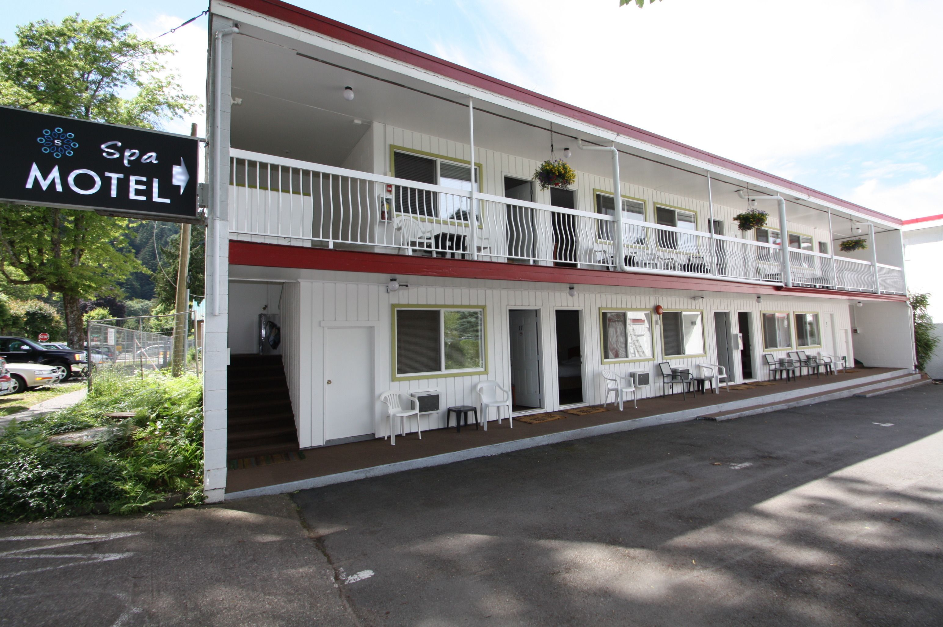 Un motel de dos pisos con balcón en el nivel superior, mobiliario exterior y un letrero que indica que es un motel con spa.