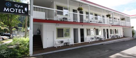 Un motel de dos pisos con balcón en el nivel superior, mobiliario exterior y un letrero que indica que es un motel con spa.
