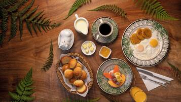A breakfast table with various food items, a cup of coffee, and a basket of rolls.