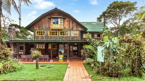A wooden building with a green roof, a porch with benches, and a pathway leading to the entrance. - Sachatamia Lodge (Mindo)