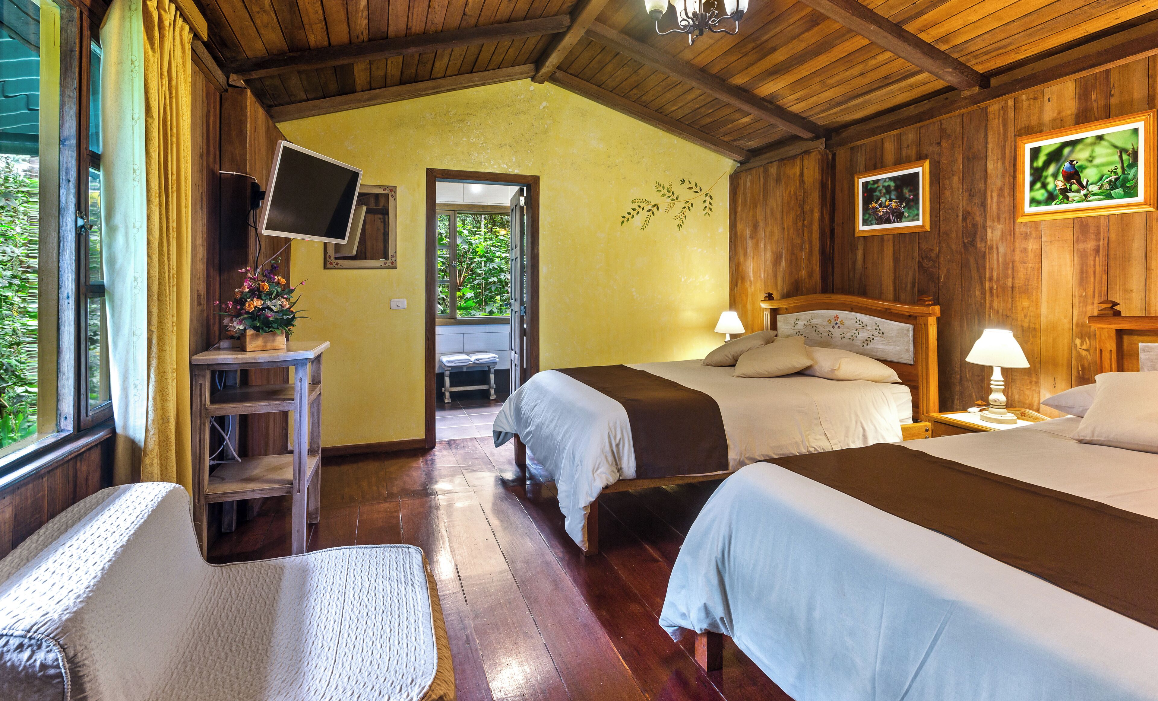 Una habitación con dos camas, un escritorio con televisor y una ventana con cortinas.