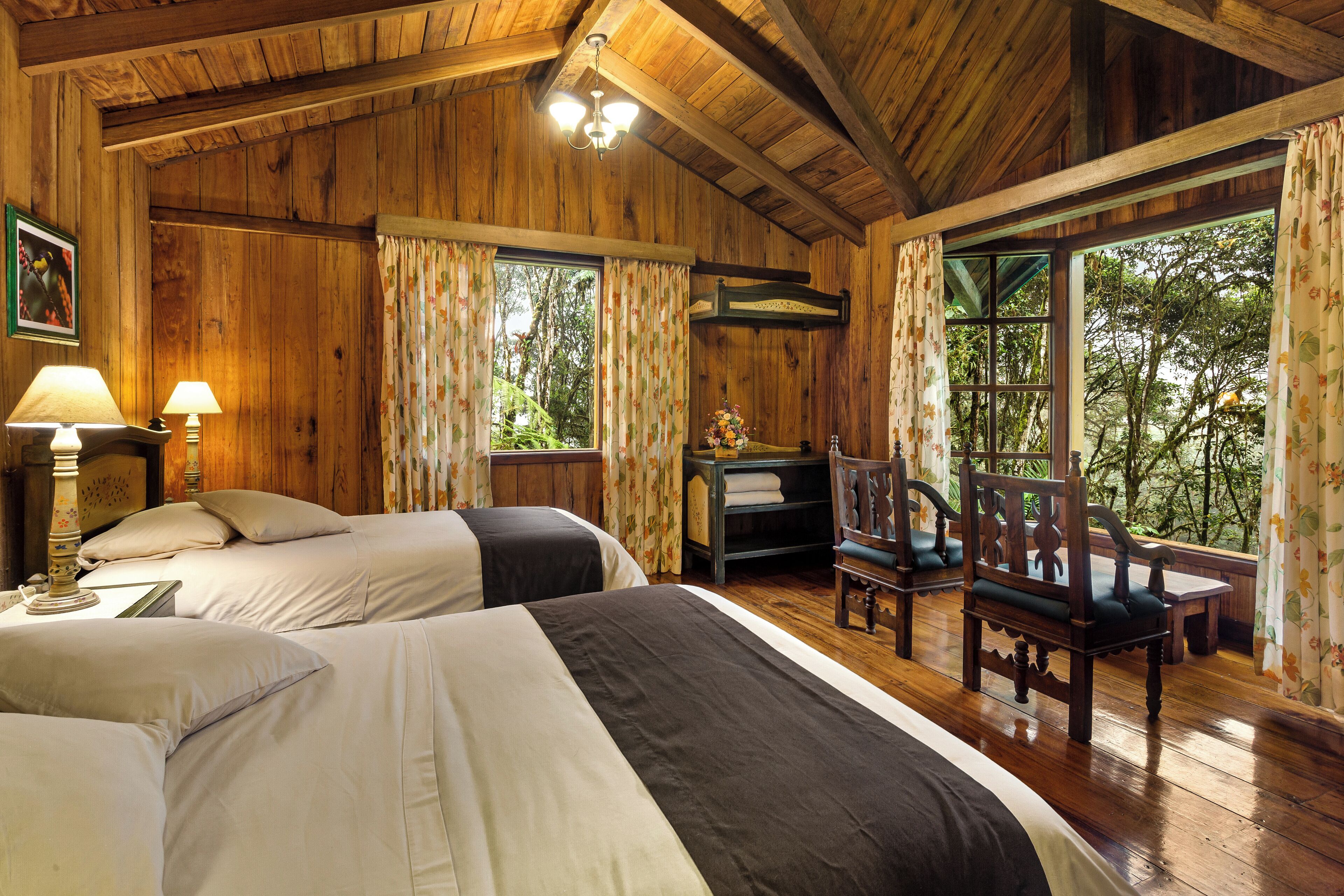 Habitación tipo cabaña de madera con dos camas, un escritorio y una silla.