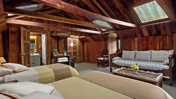 A cozy attic bedroom with wooden beams, a skylight, a sofa, and two beds.