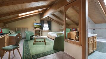 A cozy attic bedroom with a bed, a desk, a chair, and a bathroom.