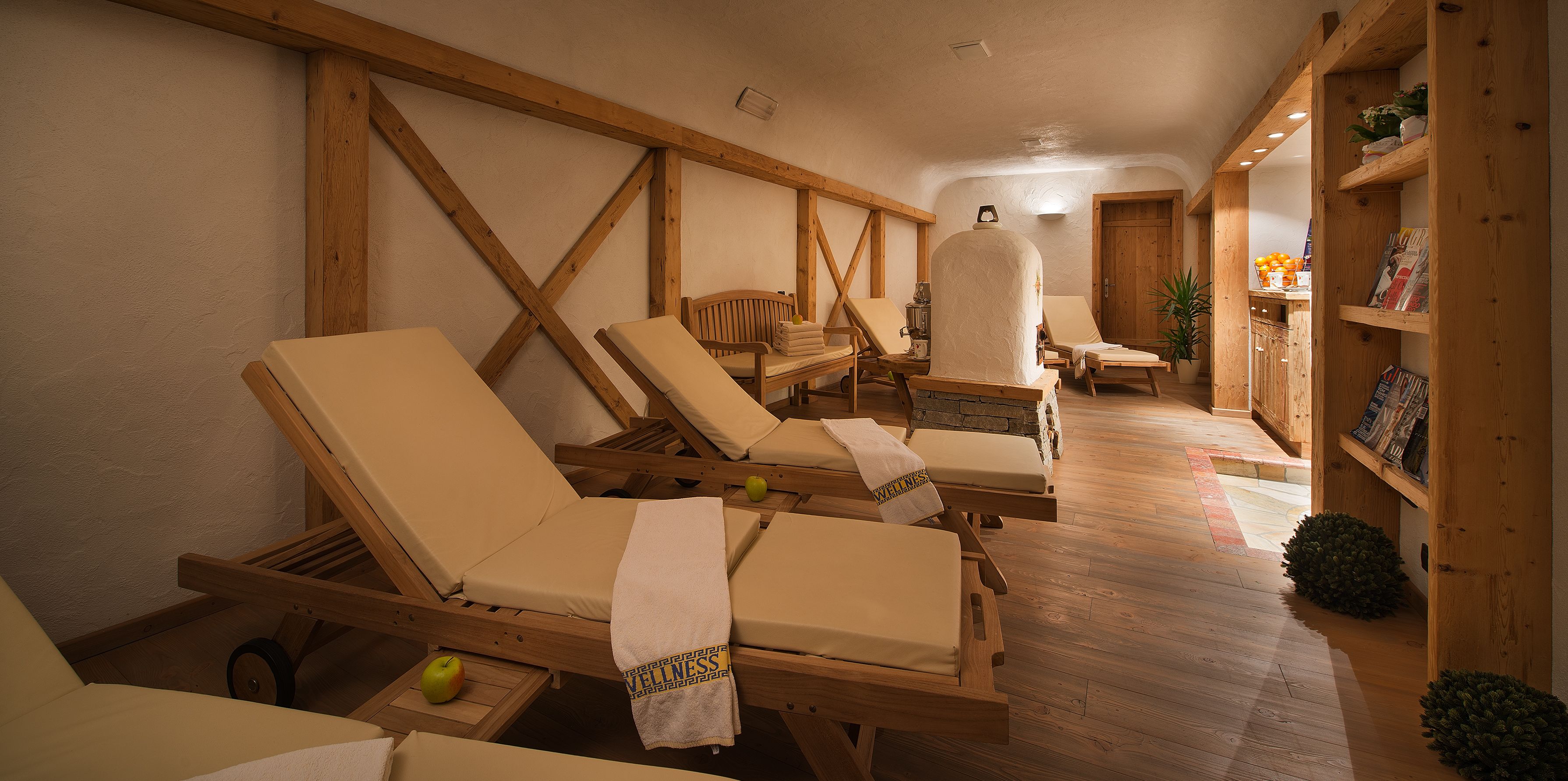 Um espaço de bem-estar com espreguiçadeiras de madeira, sauna e estantes de madeira com livros e plantas.