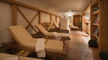 Um espaço de bem-estar com espreguiçadeiras de madeira, sauna e estantes de madeira com livros e plantas.