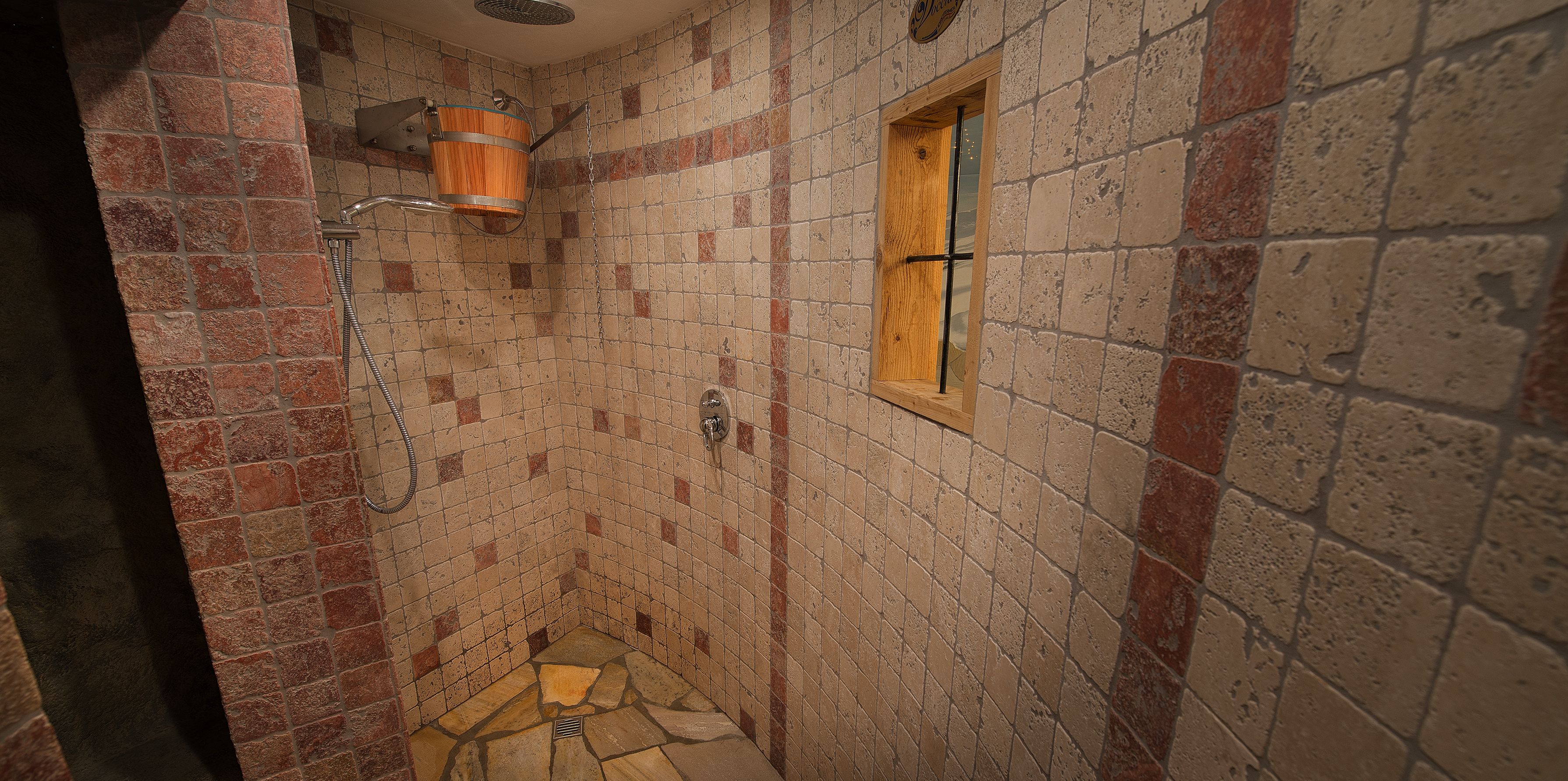 A small, tiled shower area with a wooden window and a metal showerhead.