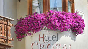 A building with a sign reading "Hotel CROSAL" and a window with a flower box. - Hotel Crosal (Livigno)