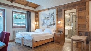 A wooden-framed room with a bed, a desk, and a painting of a snowy landscape. - Hotel Crosal (Livigno)